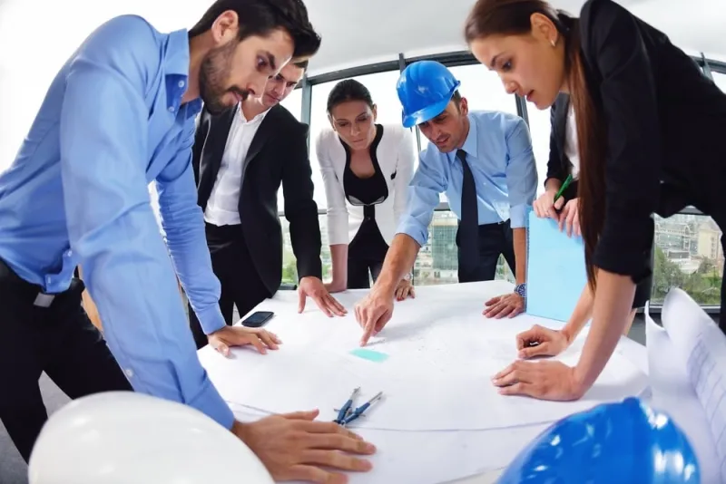 Construction team reviewing building plans and a model in a bright office